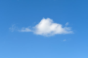single fluffy white cloud in bright blue sky
