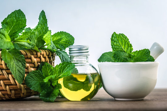 Aroma essential oil from a peppermint in the bottle on the table with fresh green mint leaf