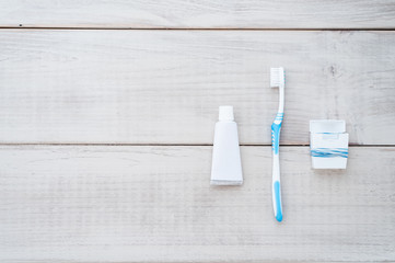 Toothbrush, toothpaste and dental floss on a weathered wood background