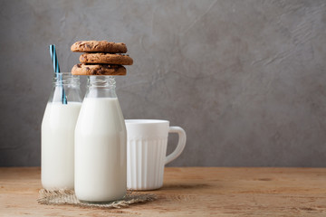 Two bottles of milk and chocolate chip cookies on dark background with copy space