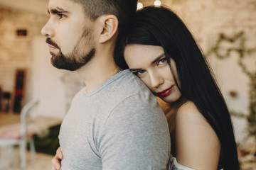 Fototapeta premium Close up portrait of a beautiful couple where girl is hugging her lover while her head is leaning on his shoulder.