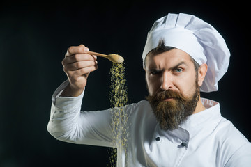 Adding seasoning. Portrait of bearded male chef sprinkling spices. Hand sprinkling spices. Cooking....
