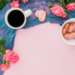 Holiday composition with roses flowers, cookies and cup of coffee on pink background. Flat lay, top view