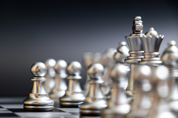 Silver pawn has first movement in chess game on black background