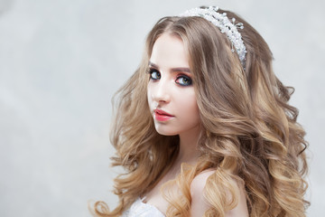 Young beautiful bride with luxurious curls. Wedding hairstyle with tiara.