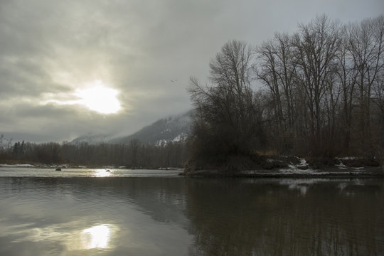 Bright sun shining through the clouds to reflect in a calm river