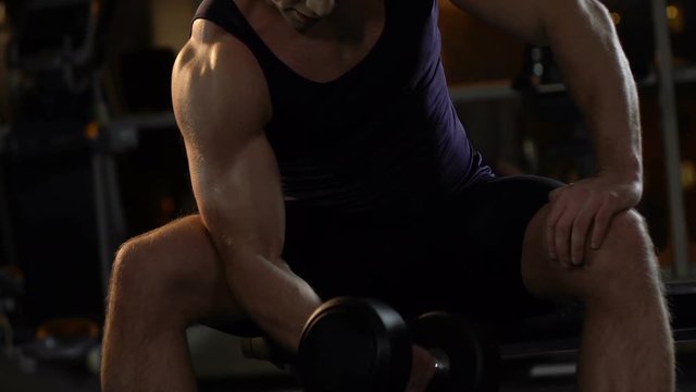 Handsome bodybuilder lifting heavy dumbbell in gym, active workout and sports