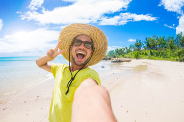 Handsome man having fun taking a selfie at the beach on holiday