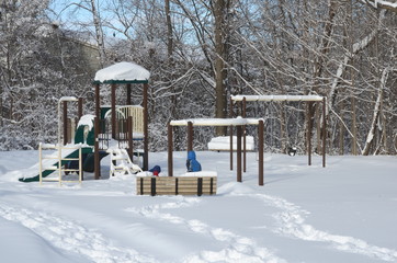 Heavy winter snow fall in Canada and unidentified children playing on a snow-covered playground in a residential area