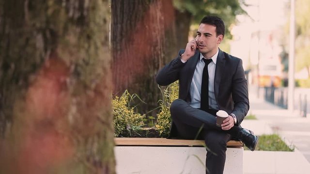 Young Business Man Talking At Phone While Drinks Coffee To Go