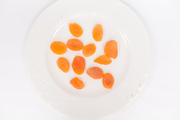 Dried apricots in a white plateon a white background