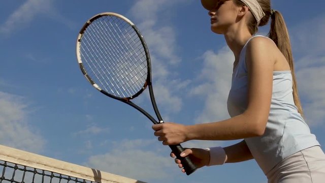 Attractive girl playing tennis on court, beginner practicing shot, slow motion