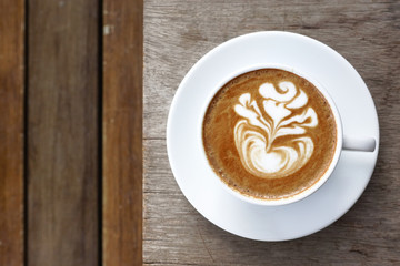 a cup of latte art coffee on wooden background