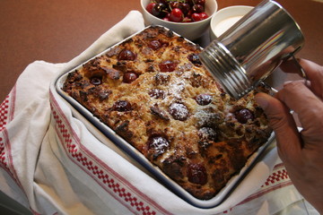 German Specialities; Soufflé with cherries Ann old bread, hand is decorating with powdered sugar
