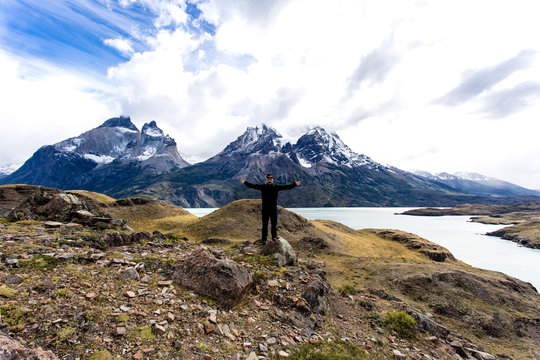 man standing with arms wide open with Torres del Paine mountain range in the background
