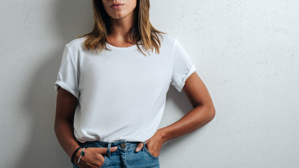 Young woman in white blank t-shirt, grunge wall, studio close-up