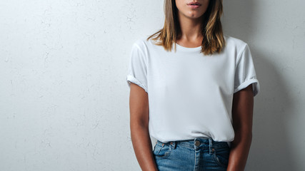 Pretty woman in white blank t-shirt, grunge wall, studio close-up
