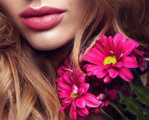 Beauty fashion portrait of young blond woman model with natural makeup and perfect skin with bright сrimson chrysanthemum flower posing in studio