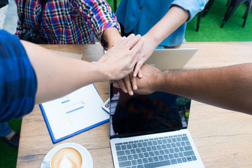 Close-up of business partners making pile of hands in meeting room, teamwork power successful meeting workplace concept