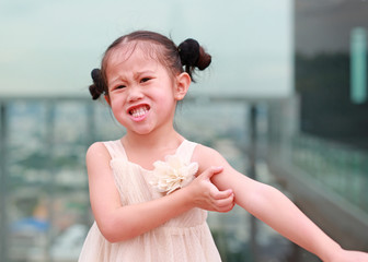Funny face of little Asian girl scratch the itch with hand. Healthcare concept.