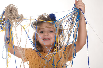 little girl holding tangled yarn of wool for knitting in her hands