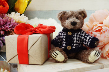 teddy bear and gift box with red ribbon on wooden background