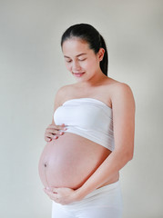Portrait of happy pregnant woman holding her hands on her belly.