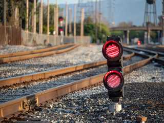 A railroad color position light flashing red stop lights with fencing to the left