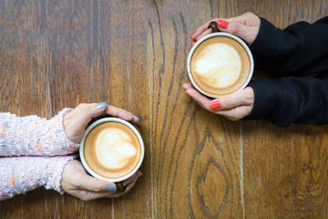 Couple woman hands holding cup of coffee on wooden table