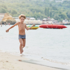 Smiling boy enjoying summer vacation and playing on the beach, image with square aspect ratio