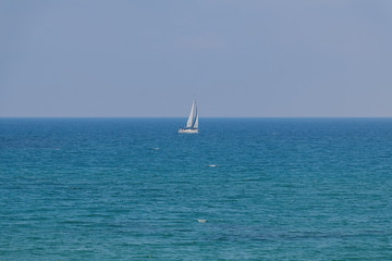 Fototapeta na wymiar White sailboat floating on a calm sea.