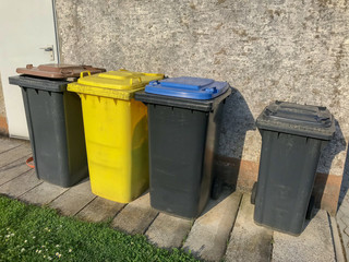 Verschiedene Mülltonnen an einer Hauswand