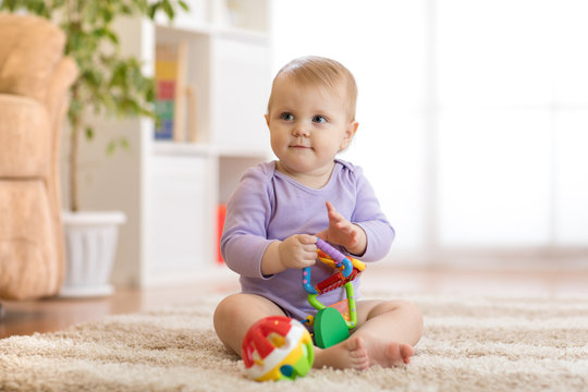 Smart baby girl with educatinal toys in sunny nursery room