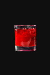 A single-colored transparent cocktail, refreshing in a low glass with ice cubes and taste of berries, cherries, strawberries, greiprut. Side view. Isolated black background. Drink for the menu