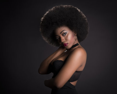 Beauty black girl with afro hair in a black background with light and smoke behind her