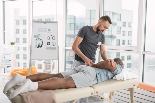 Professional therapy. Smart professional therapist using a special technique while doing massage for his patient