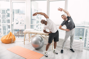 Sport is life. Pleasant nice men exercising while doing rehabilitation therapy