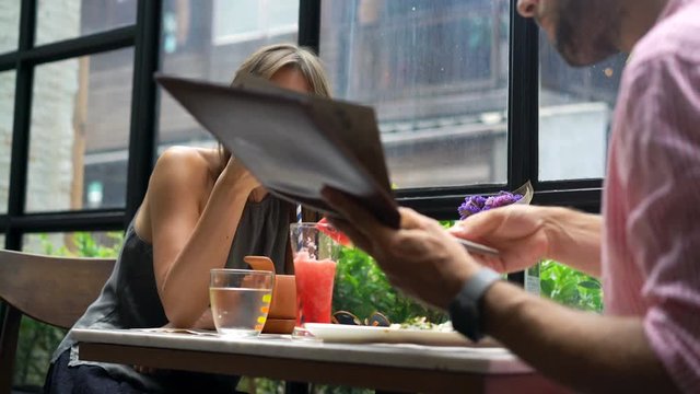 Young couple eating dinner and reading menu in cafe 
