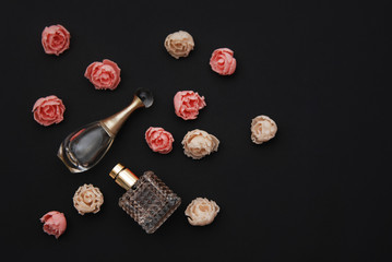 Bottle Perfume and Fake Roses on dark Black Background with copy Space Text flat Lay Top view