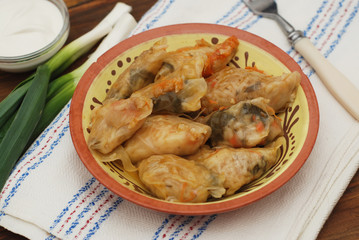 Stuffed Rolled Cabbage meat in Leaves in a Ceramic Plate with White Napkin,Parsley on a Rustic Wooden background. Traditional Romanian Russian Ukrainean Food.