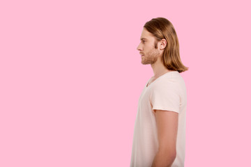 Always looking forward. Charming young man with a longish hair standing sideways to the camera and...