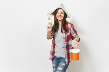 Young overjoyed beautiful woman in newspaper hat blinking and holding paint brush and paint bucket isolated on white background. Instruments, tools for renovation apartment room. Repair home concept.