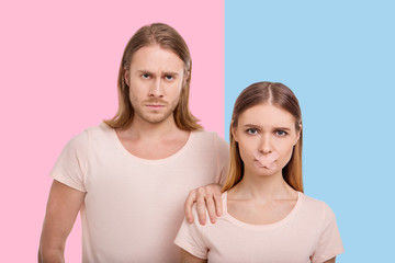 Without rights. Scowling young man having a hold of his girlfriends shoulder while she having her...