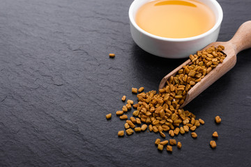 fragrant grains of fenugreek on a rustic background