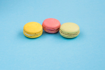 Macaroons, pink, yellow and green macaroons on blue background with wedding rings. Bright and colorful concept. Copyplace, place for text.  Wedding rings near macaroons on blue background. Copyplace, 
