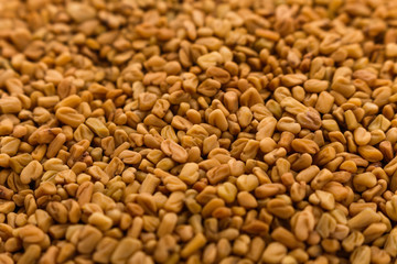 fragrant grains of fenugreek on a rustic background