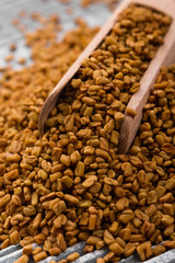fragrant grains of fenugreek on a rustic background