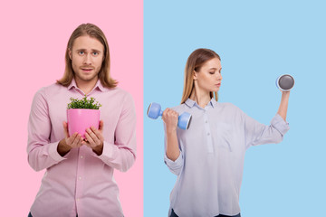 Different preferences. Charming slim woman making exercising with dumbbells while her boyfriend...