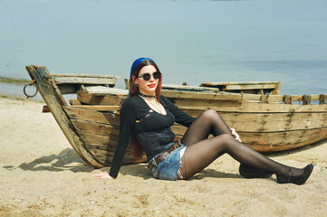 stylish fashionable young girl on the beach .Girl sitting on an old boat