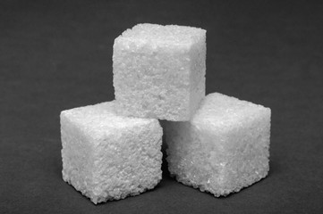 macro shot of a three cubes of sugar on a dark gray surface